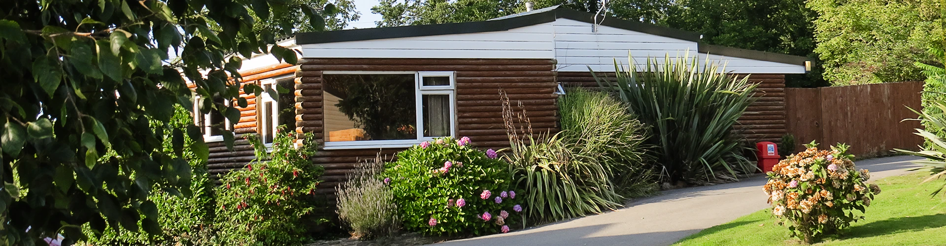 Page header. Image of the lodge surrounded by flowers and in sunlight